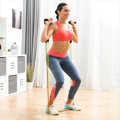 dans le salon femme exerce flexions squats avec elastique musculation