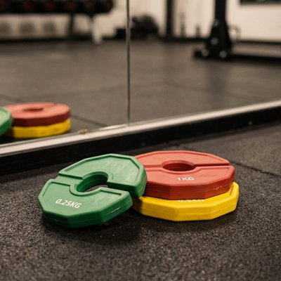 disque musculation vert rouge jaune face a un miroir