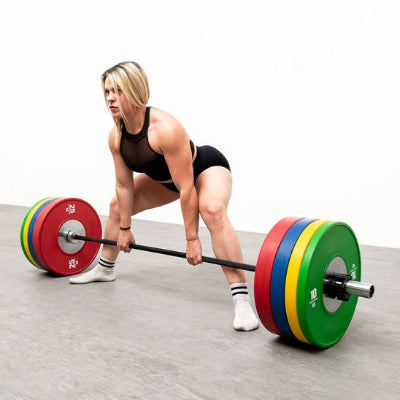 Femme musclée se prépare à soulever disque musculation