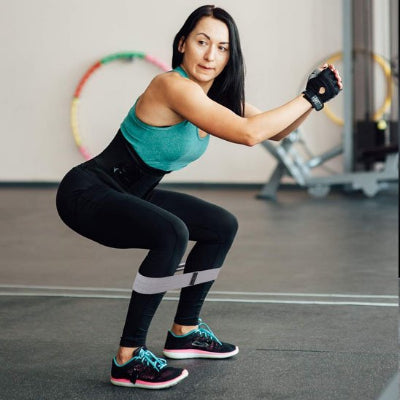 Femme position squat Elastique musculation​ en bas des genoux