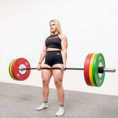Femme réalise un soulevé de terre deadlift avec disque musculation
