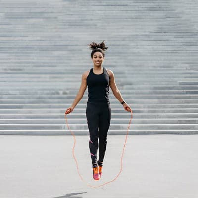 Fille bronze pieds croises saute avec sa corde à sauté