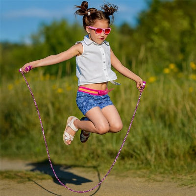 fillette avec lunettes de soleil saute avec corde a sauter