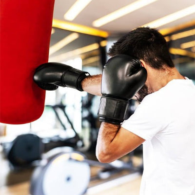 Gants de boxe noir sac de frappe rouge bras tendu