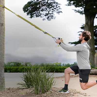 Homme exercice plein air TRX avec sa musculation sangle