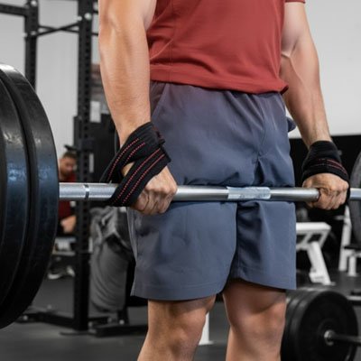 Homme soulève sa barre musculation avec ses sangles de tirage