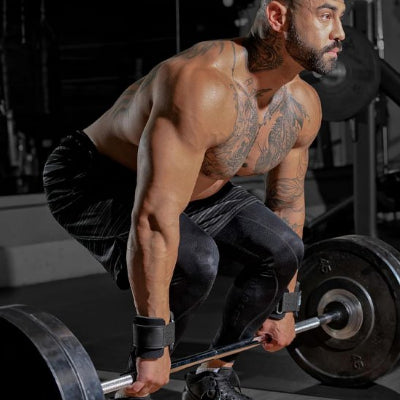Homme tatoué torse nu fait musculation avec sangle de tirage