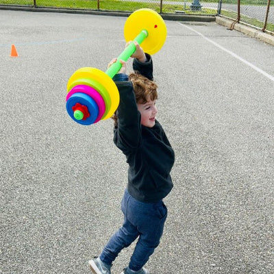 Jeune garçon dans une cour soulève bout des bras haltère 