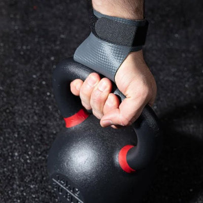 Main portant un gant pour musculation gris tenant une kettlebell noire