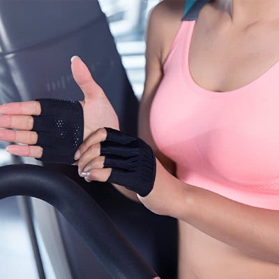 Sportive portant gant musculation noirs sur un appareil de fitness