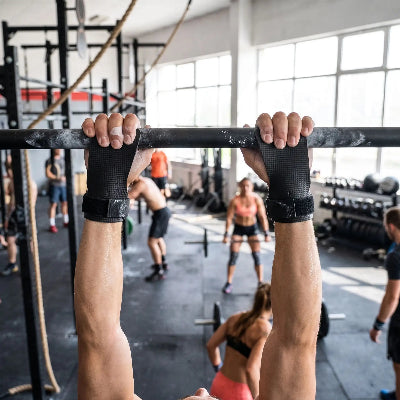 Suspendu a une barre de traction avec gant pour musculation noir